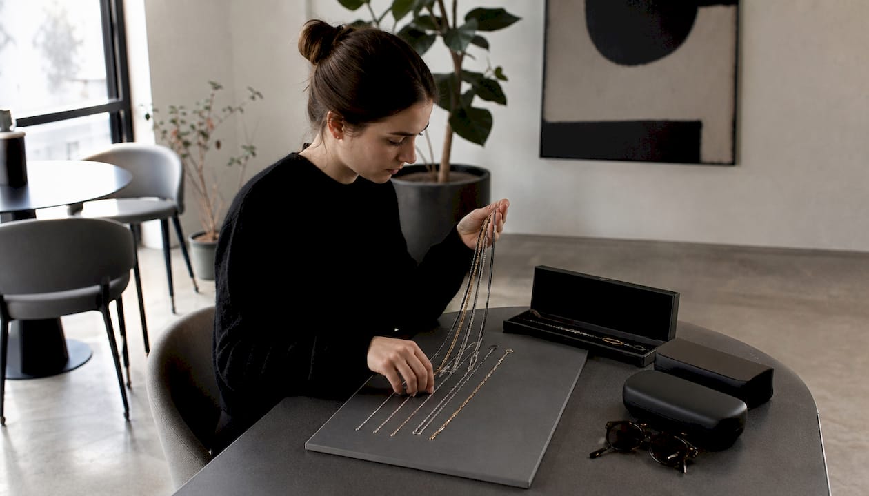 Eine Frau stellt ihre Schmuckstücke zusammen, um sie im angesagten Layering-Look zu kombinieren.